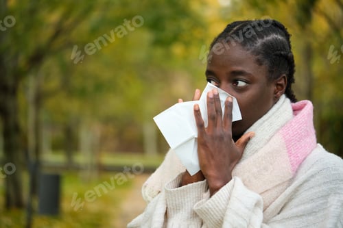 Preview: African woman blowing nose into tissue during winter. Flu.