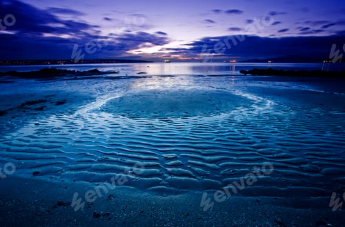 Preview: A beach at low tide under a darkening sky. Ripple pattern on the sand.