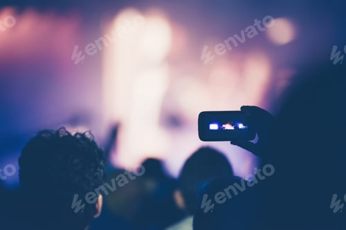 Preview: Fan taking photo of concert at festival with a mobile phone