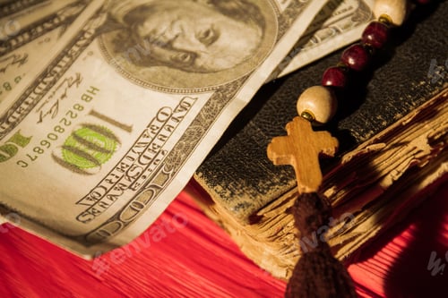 Preview: Close up old book, wooden cross on bead necklace and money.