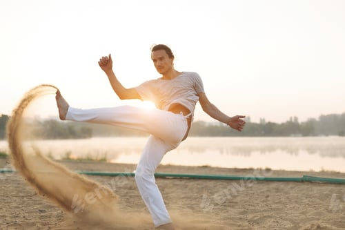 Preview: Athletic capoeira performer workout training on the beach sunris