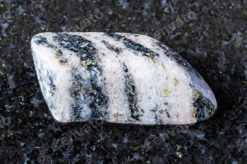 Preview: sample of tumbled gneiss mineral on black granite