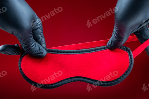 Preview: hands in black gloves holding a red erotic bandage for bdsm games