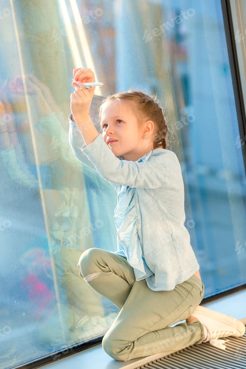 Preview: Little girl in airport near big window while wait for boarding