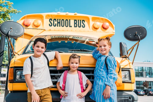Preview: group of adorable pupils leaning back on school bus and looking at camera
