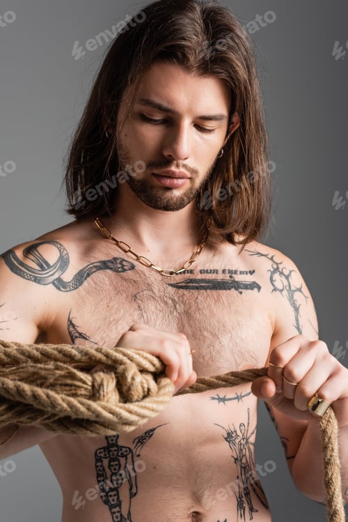 Preview: Sexy and tattooed man holding rope isolated on grey
