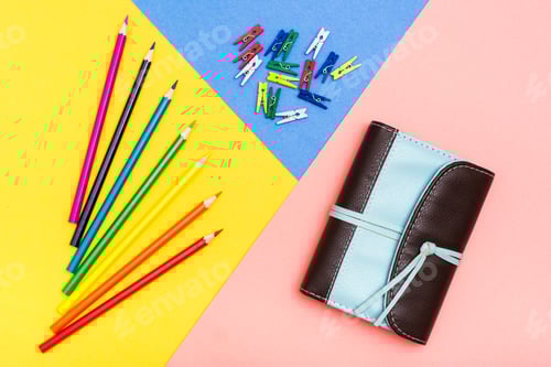 Visualização: Lápis de cor, prendedores de roupa coloridos e organizador em um fundo tricolor. Paleta arco-íris