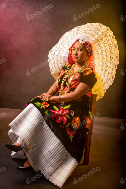 Preview: A woman in a colorful dress sits in front of a wall