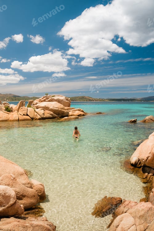 Preview: Tourist walking in the crystal clear water of sardinia beaches during summer holidays