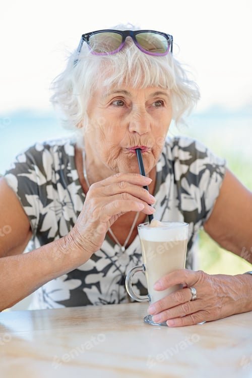Preview: Attractive senior woman sitting in a summer outdoor cafe