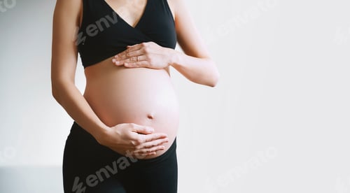 Visualização: Mulher grávida segurando suavemente as mãos na barriga durante a gravidez.