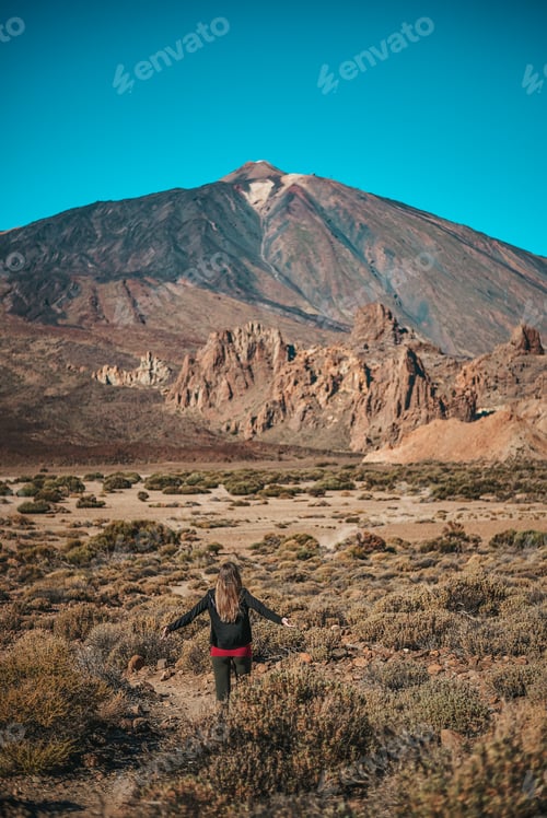 Preview: Young woman contemplating Roques de Garcia formation with the Teide volcano in the background