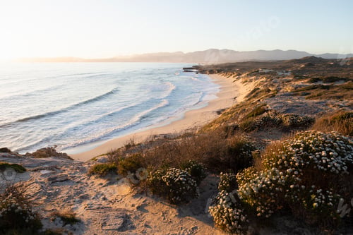 Preview: View from the cliffs over the sandy beach and waves breaking on shore.