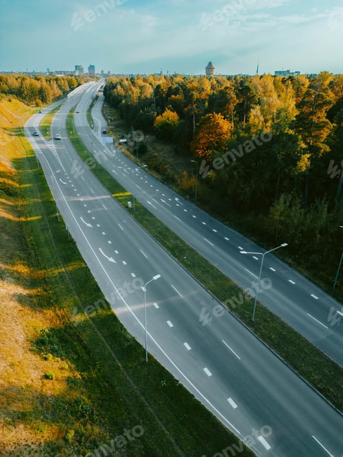 Preview: Vertical top view of cars driving along a highway road in the evening time under a sunny blue sky