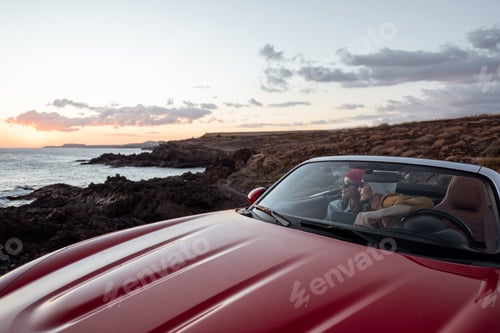 Preview: Couple driving convertible car near the ocean
