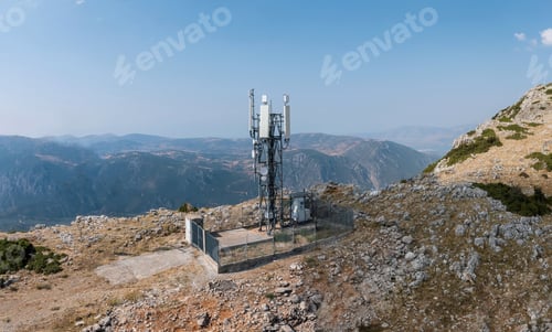 Preview: Cell tower. Mobile phone antenna aerial view. Rocky mountain and blue sky
