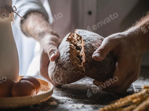 Preview: Men's hands in flour break off a piece of fresh homemade bread. Home bakery