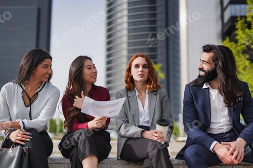 Preview: Diverse young business people sitting outside of office building doing a break toghether