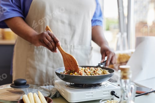 Preview: Close up of black woman frying vegetables in kitchen cooking healthy meal