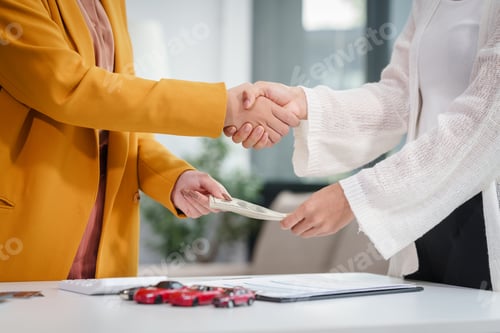 Preview: Asian business woman hands car keys to a customer while a salesman discusses car sales, insurance