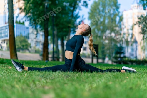Preview: A young beautiful girl sits on splits and does stretching after training in the morning in the park