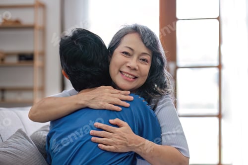 Preview: Two retired Asian women hug as they meet and have fun in the living room.