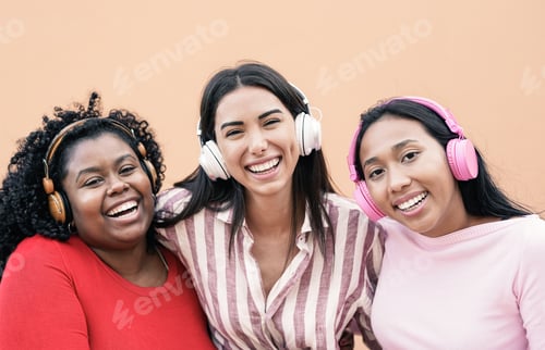 Preview: Multiracial girls wearing wireless headphones while smiling on camera