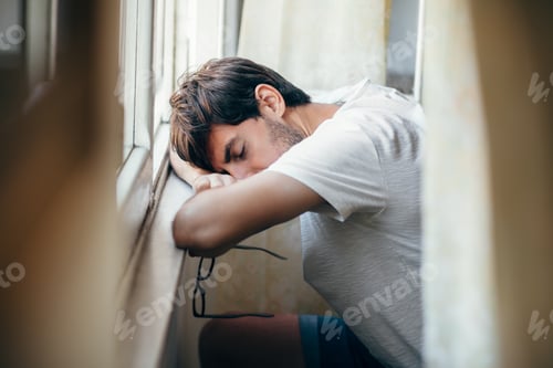 Preview: Tired young man sleep near window
