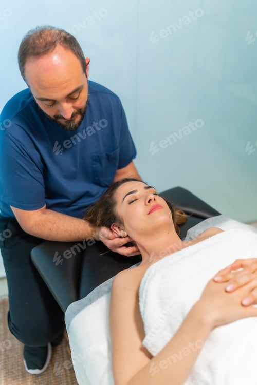 Preview: Physiotherapist performing neck adjustment and wellness treatment on woman