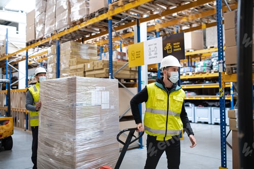 Preview: Group of workers with face mask working indoors in warehouse, coronavirus concept.