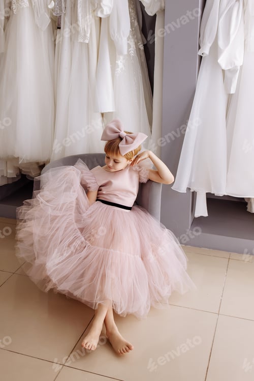 Preview: Girl in a lush pink evening dress in a clothing boutique