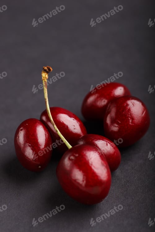 Preview: Ugly weird red sweet cherry on black background. side view.