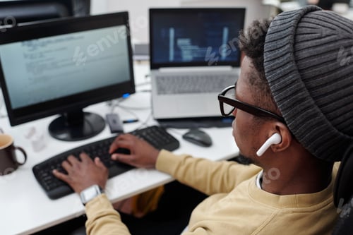 Preview: Above angle of young black man in casualwear listening to music in earphones