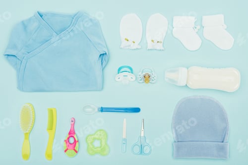Preview: top view of baby clothes and equipment isolated on blue