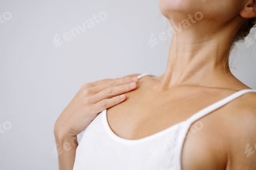 Preview: Woman wearing white top touching her skin