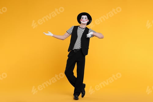 Preview: Funny mime artist in hat posing on orange background
