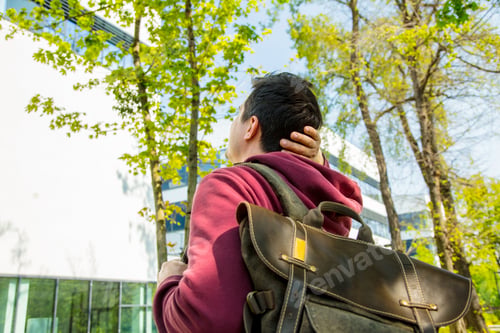 Preview: Young man with backpack stay on alley near modern building