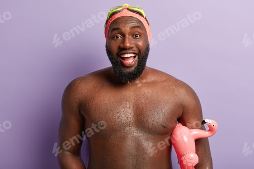 Preview: Happy unshaven muscular guy has good mood after swimming and diving in sea, smiles broadly, carries