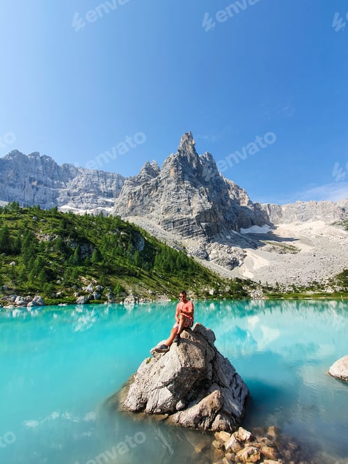 Preview: A men enjoys the serene beauty of turquoise water and mountains Lago Di Sorapis Dolomites