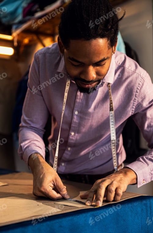 Preview: Male fashion tailor working on the measurements for the suit design in his workshop.