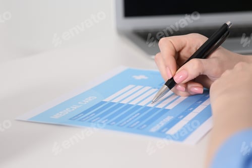 Preview: Doctor filling patient's medical card at table in clinic, closeup