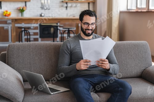 Preview: Excited Arabian man holding document, paper notification, job promotion, loan approval