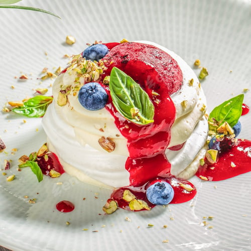 Preview: Delicate pavlova dessert with cream, blueberry, pistachio, and berry sauce
