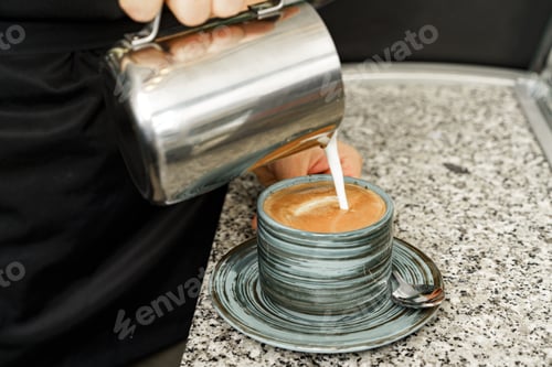 Preview: Cappucino preparation process. Hands of a woman pouring milk into a cup