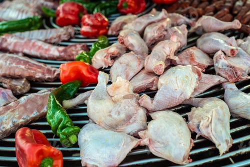 Preview: Thighs and raw chicken drumsticks on a barbecue grill.