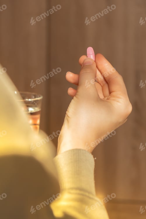 Preview: Female hand holding glass of water and pink pill. Collagen supplement for nutrition. Healthy eating