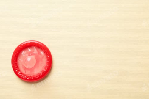 Preview: Single red condom on beige background, space for text