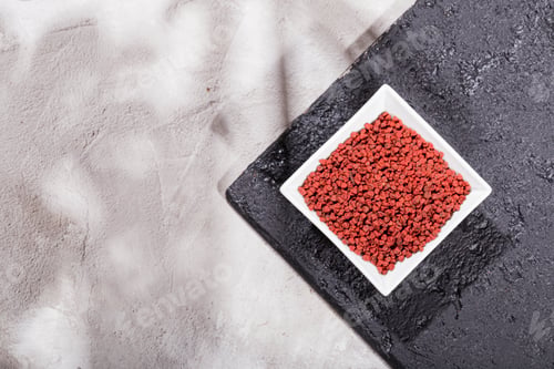Preview: achiote grains in wooden bowl on white background (Bixa orellana)