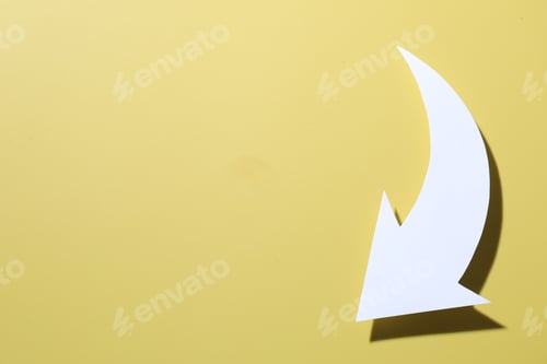 Preview: One white paper arrow on yellow background, top view. Space for text
