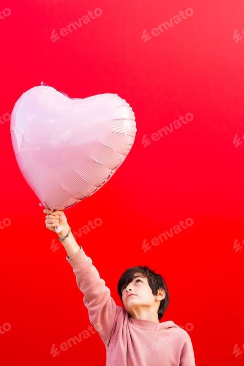 Preview: Youngster holding heart-shaped balloon on red background
